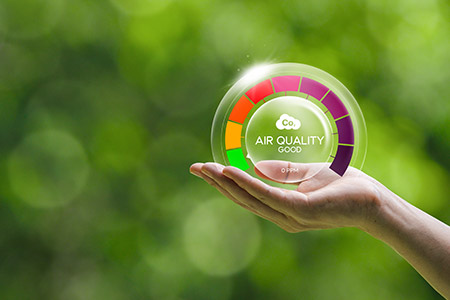 A woman holds a bubble that says “Air Quality” with a circle of multi-colored dashes.