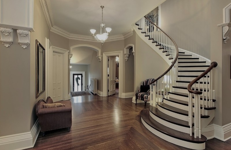 A grand staircase leads upstairs at the entrance of a luxurious home.