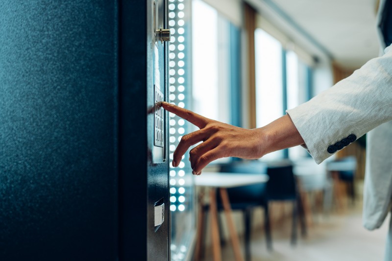 A woman pushes a button on a vending machine.