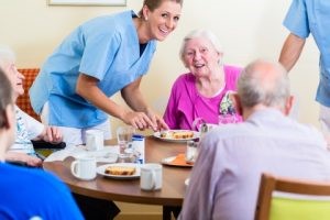 Care worker serving food to a senior resident