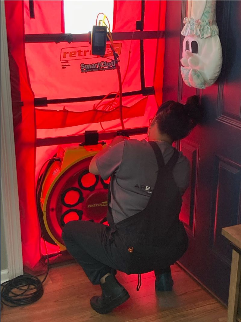 A man installs air testing equipment near a door.