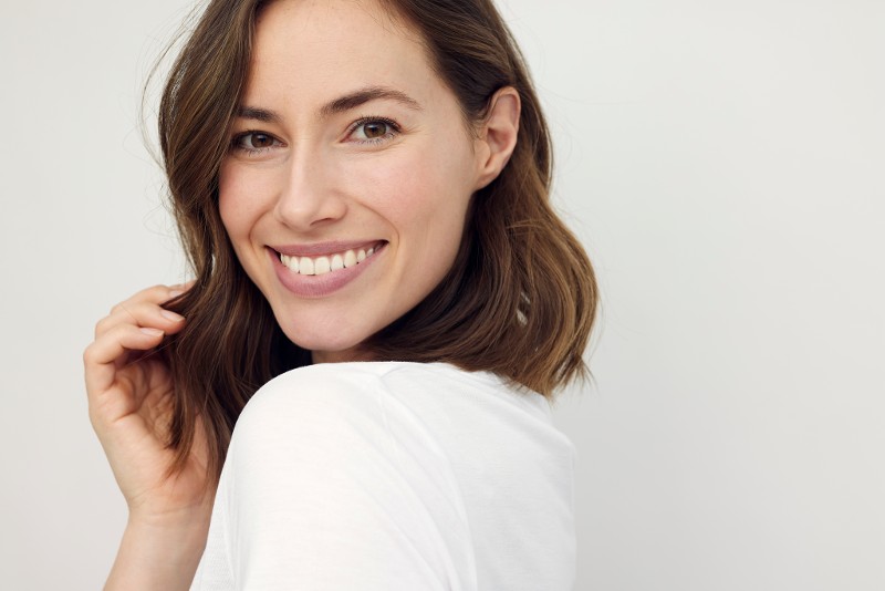 A woman tilts her head to the camera while smiling.