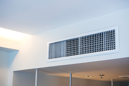 A white air duct at the top of a room.