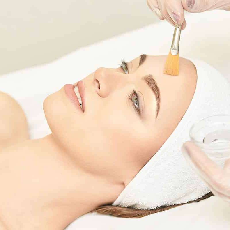 Woman lays on her back as she gets a chemical peel treatment.