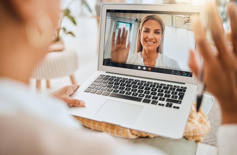 Male doctor video chatting with patient on laptop in office