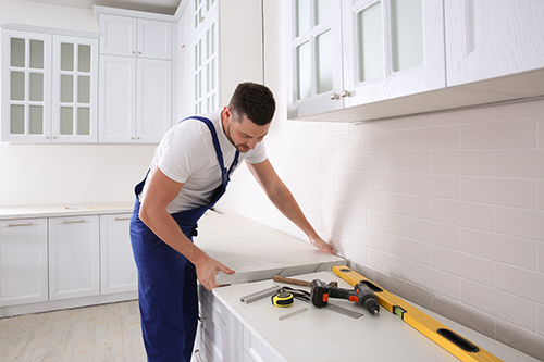 A man measures countertops in a kitchen.