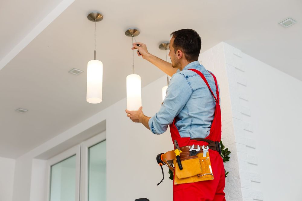 Electrician installs ceiling lighting.