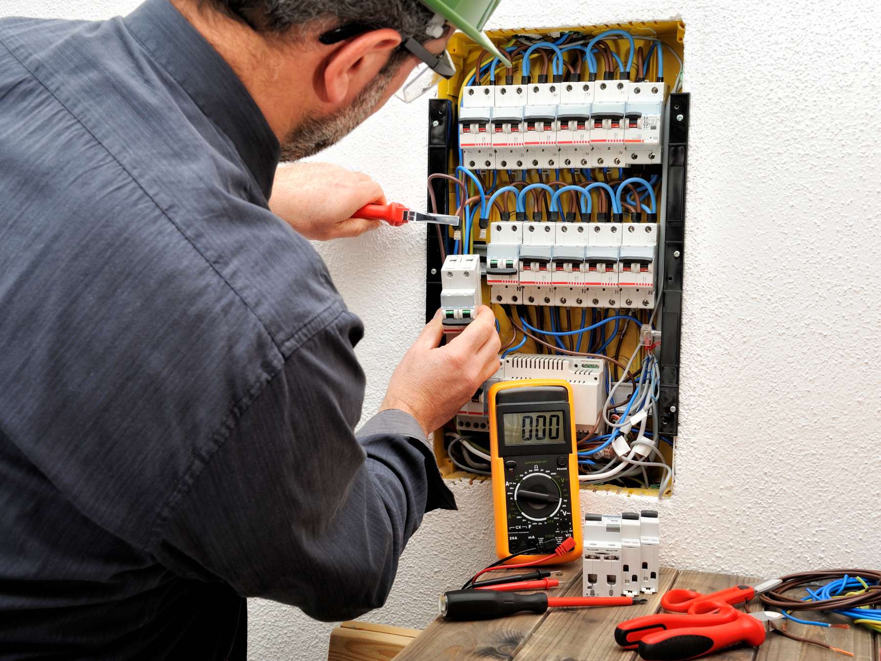 A man checks electrical connections with a voltage meter.
