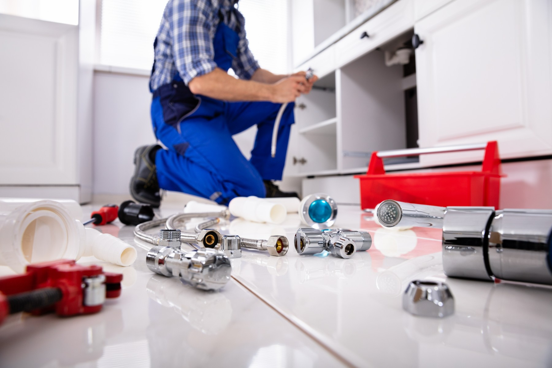 plumber with tools working under the sink