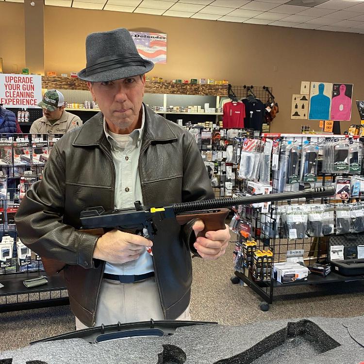 A man holds a rifle at a display counter.