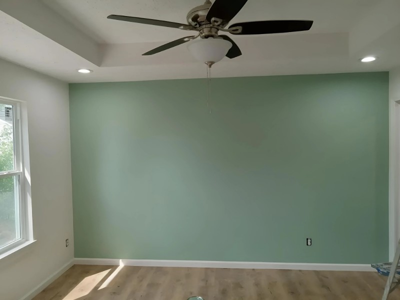 An open bedroom with a fresh coat of light green paint.