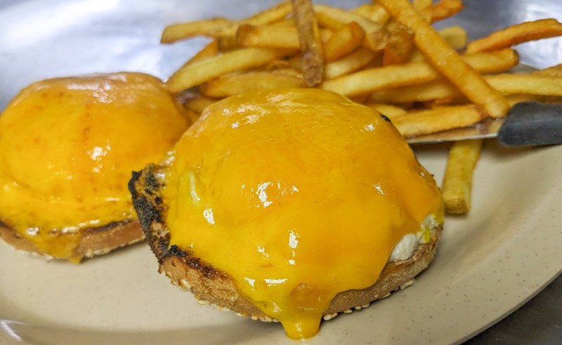 A bagel sandwich with cheese and fries.