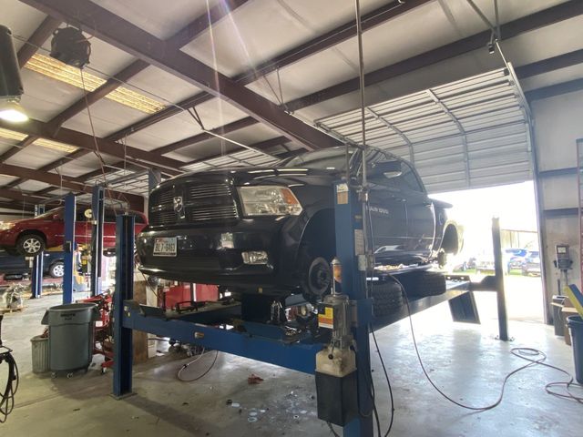 A pickup truck is raised on a lift in an auto repair shop.