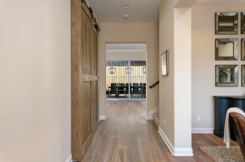 Interior hallway of house, new paint and wood floors, dining table visible in background