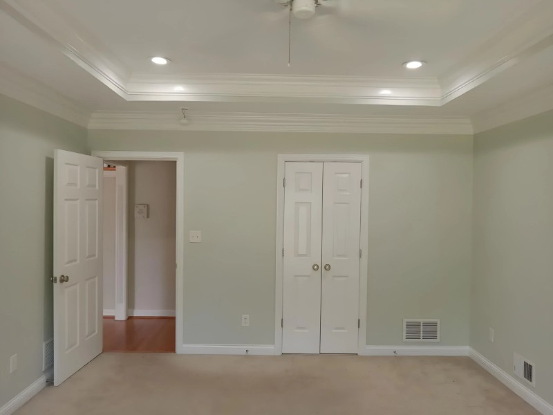 An open bedroom with a fresh coat of light green paint.