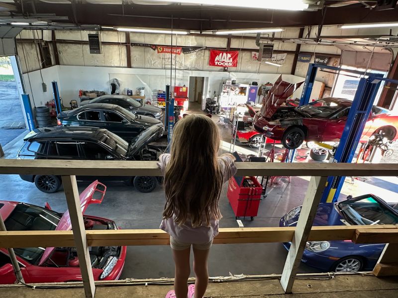 A young child overlooks an auto body shop floor