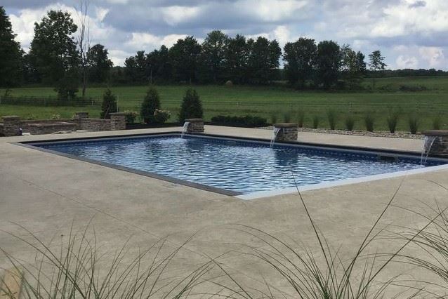 A rectangular pool is surrounded by a wide concrete patio area.