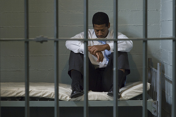 man sitting somberly in a jail cell