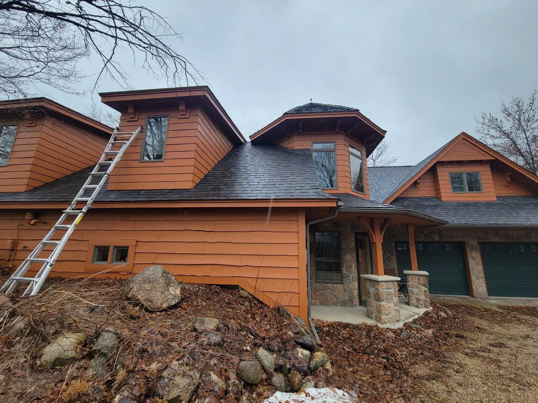 An extension ladder reaches up to the dormer of a home.