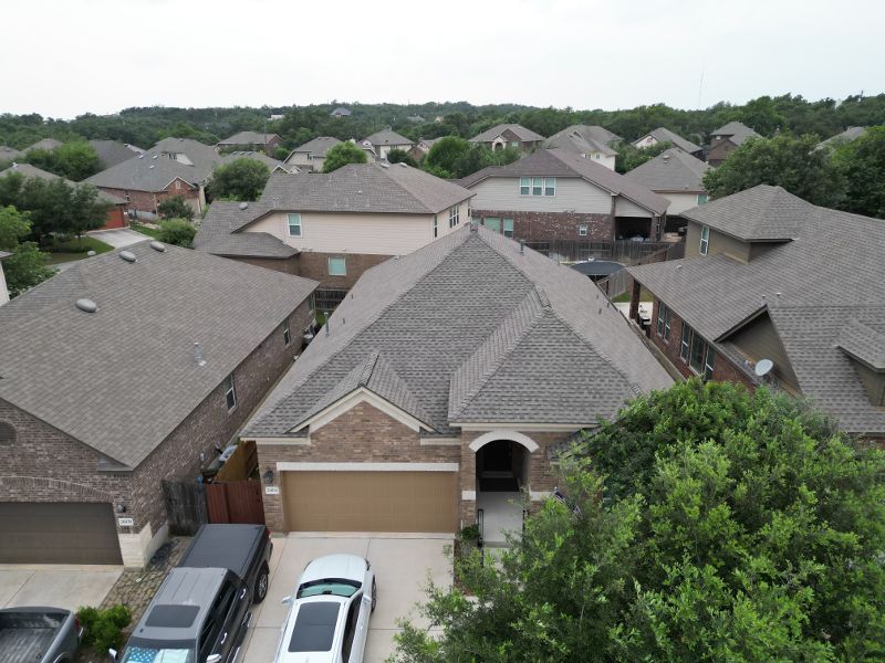 Numerous home sit close together with brown shingled roofs.