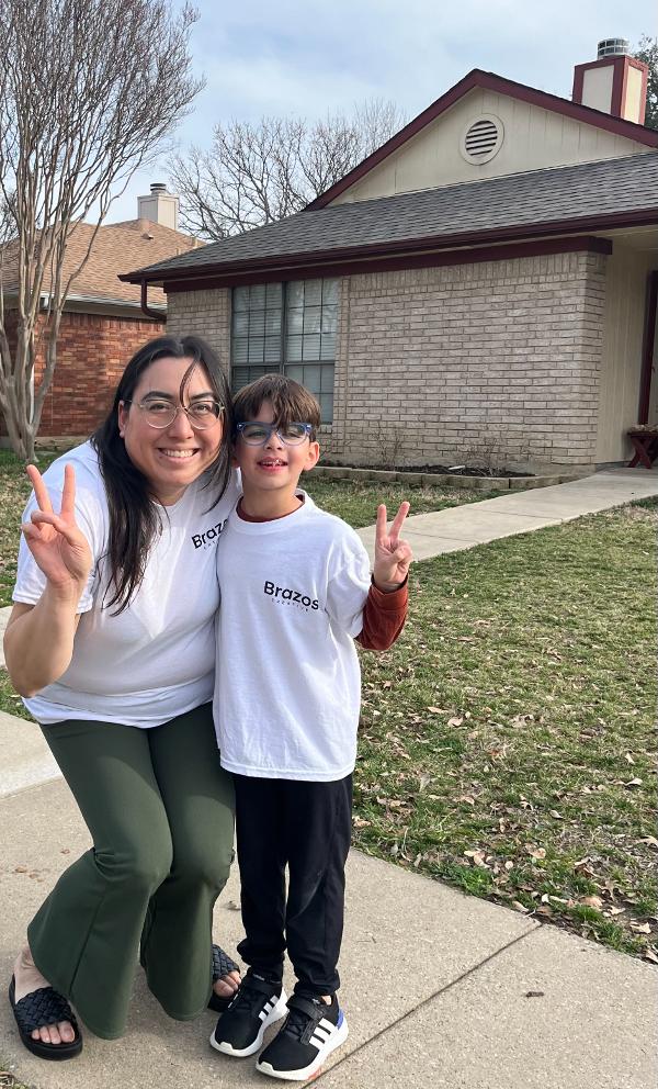 Founder of Brazos Creative smiles and holds up a peace sign with one of her students.