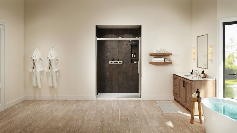 A modern, open bathroom with sliding glass doors on a tiled shower, two clothes hooks on the left, and a single-sink vanity and freestanding tub on the right.