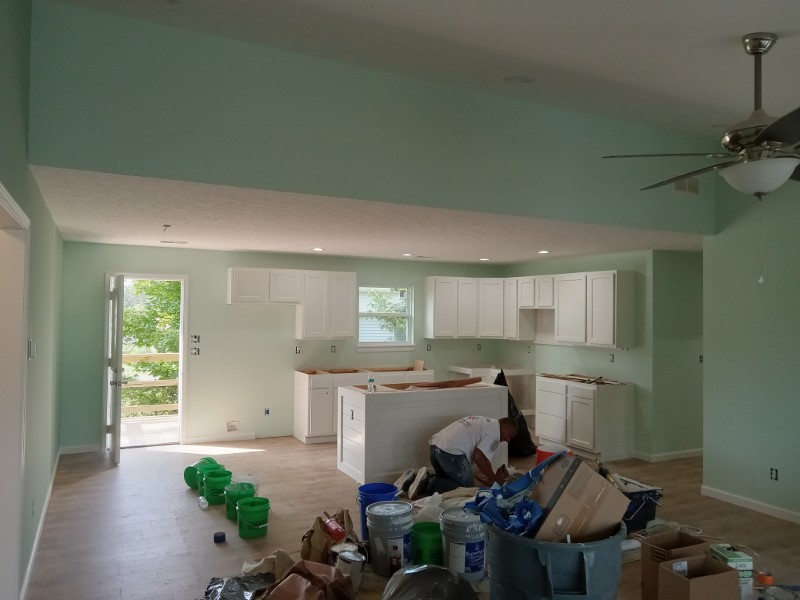 A freshly painted living room with furniture moved to the center of the room.