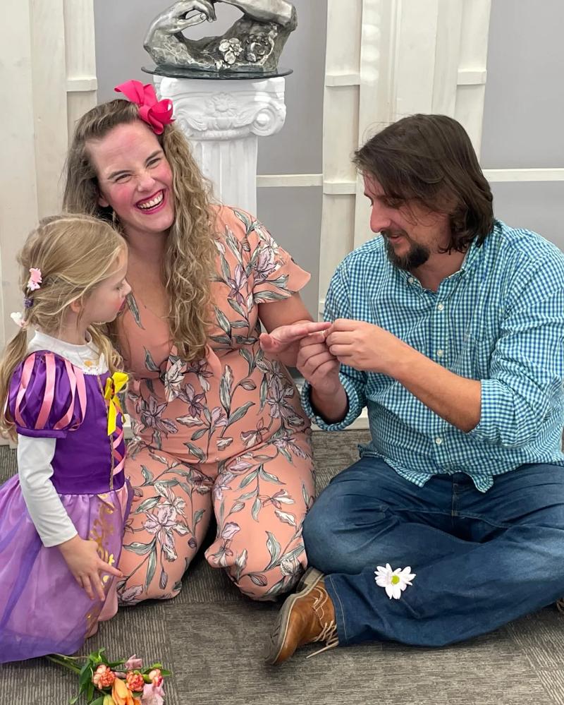 A man and woman share a laugh while a young girl watches them.