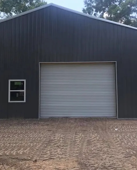 White metal roll-up door on a dark metal outbuilding.