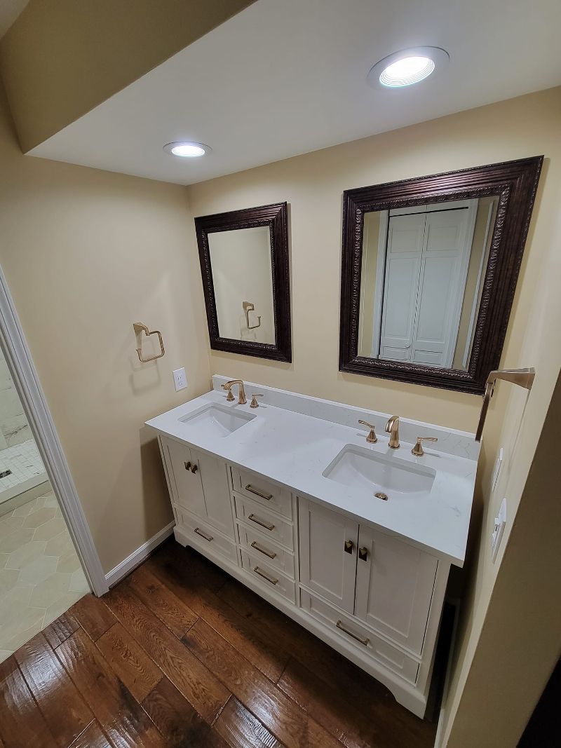 A bathroom makeover with dark hardwood flooring and a white double-sink vanity.