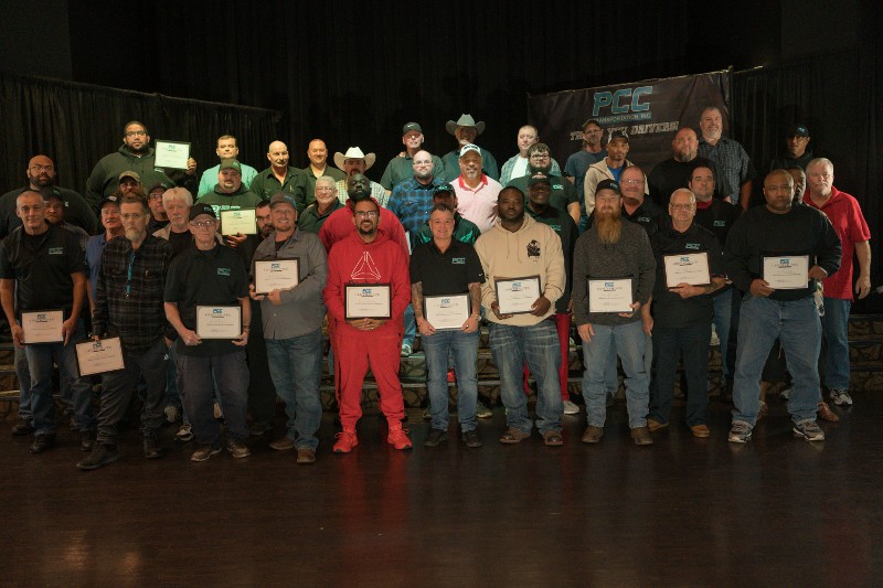 A group of PCC Transportation employees poses for a photo with many holding plaques.