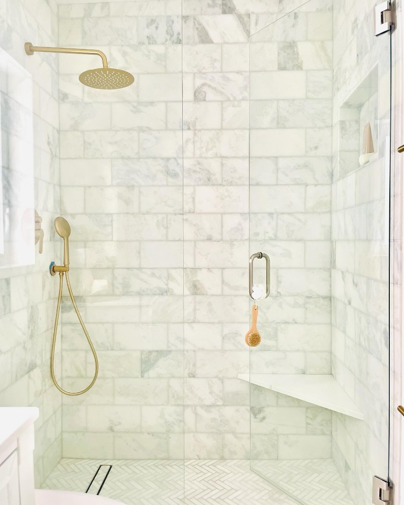 A modern tile shower with gold fixtures.