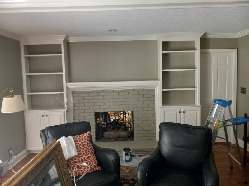 A freshly painted living room with furniture moved to the center of the room.