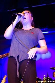 A young girl sings into a microphone.