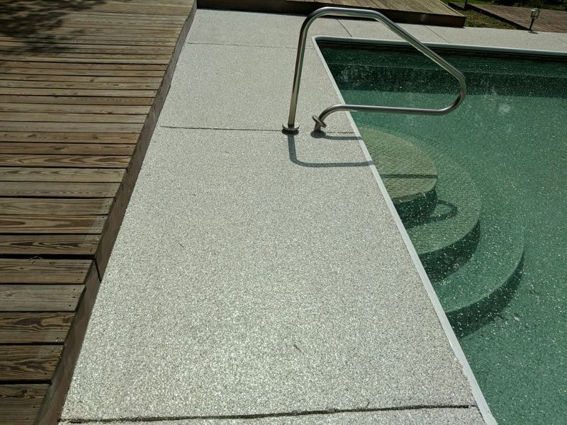 Speckled concrete coating around a pool.