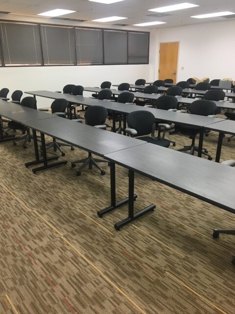 A conference room is filled with four rows of tables and chairs.