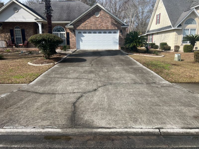 The view of a home's driveway needing pressure washed.