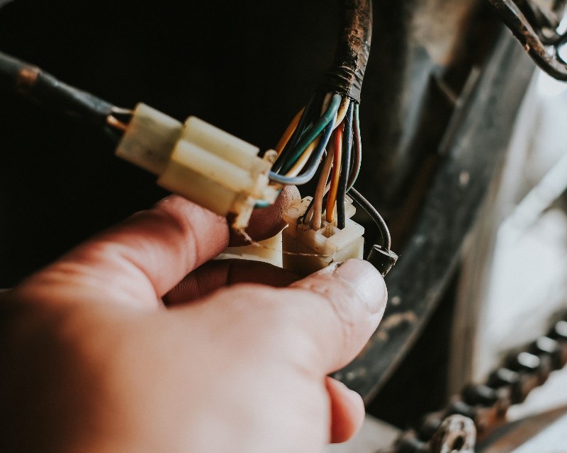 A mechanic inspects electrical connections.