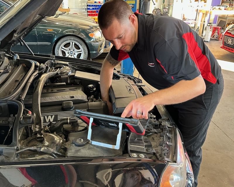 A mechanic uses diagnostic tools in car’s engine