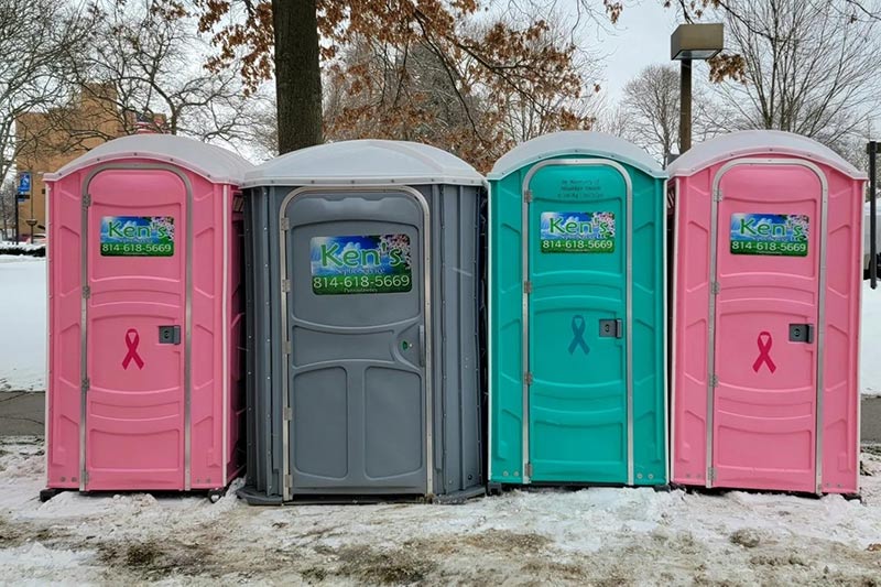 A row of four colorful portable toilets.