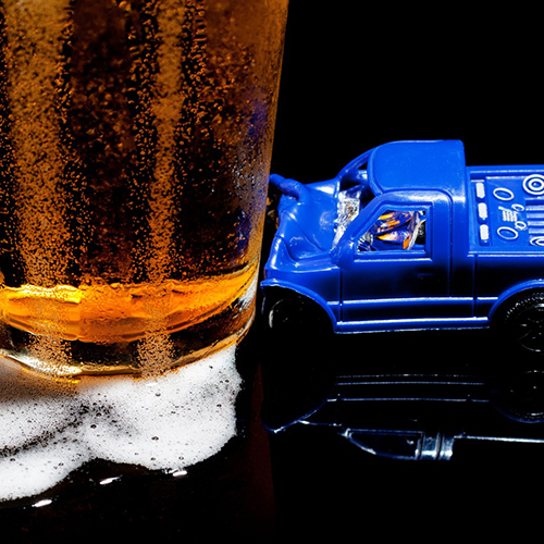A toy truck has crashed into a glass of beer.