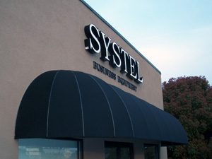 A wrap-around black awning for the building of Systel Business Equipment.