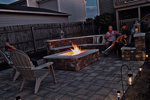 people sitting at an outdoor firepit at night