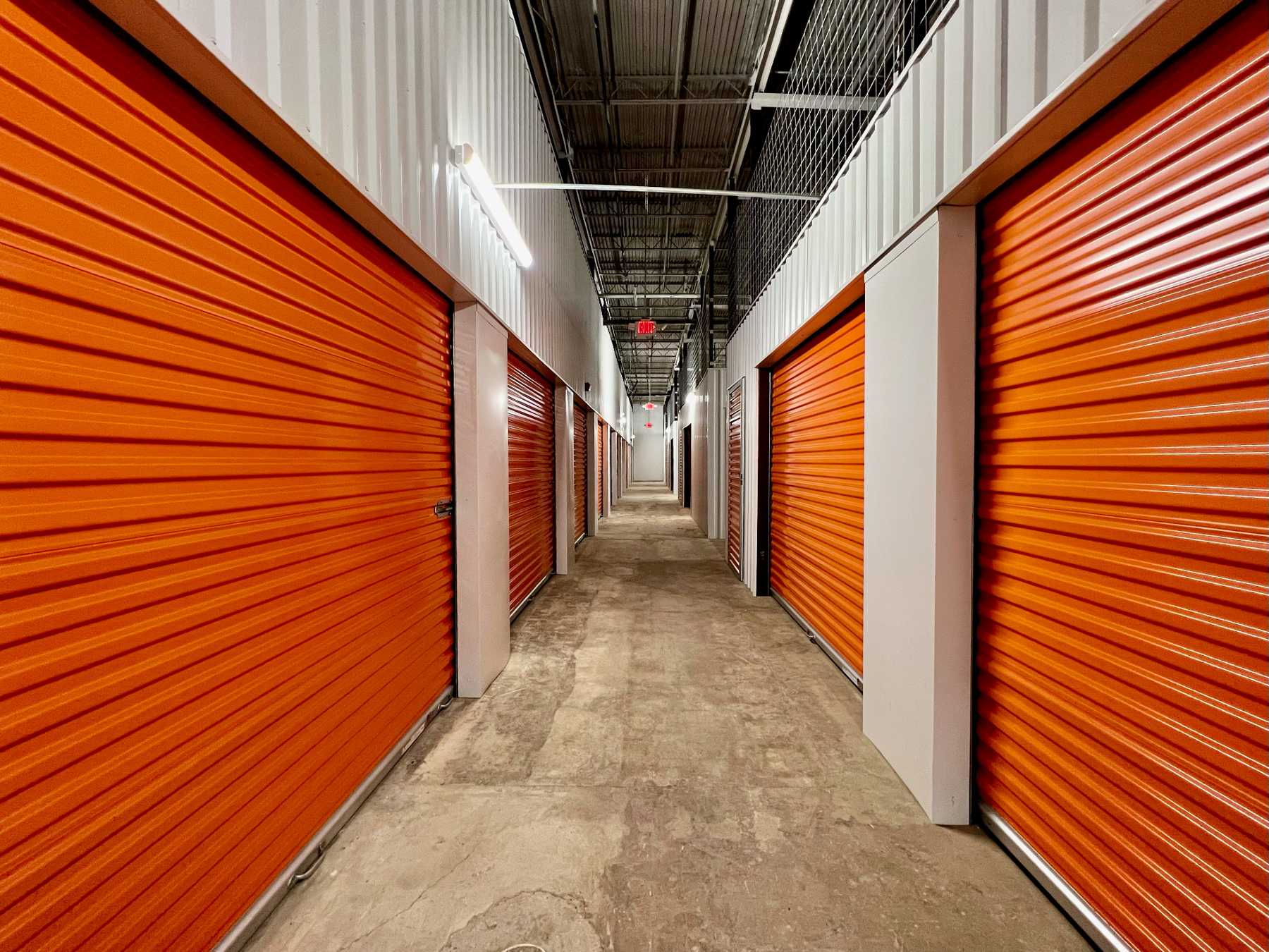Corridor of storage units with orange doors.