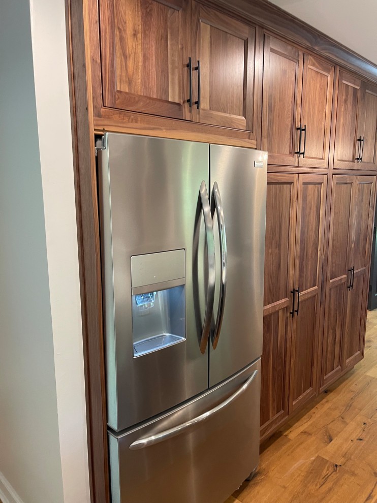 Wooden kitchen cabinets surround a refrigerator.