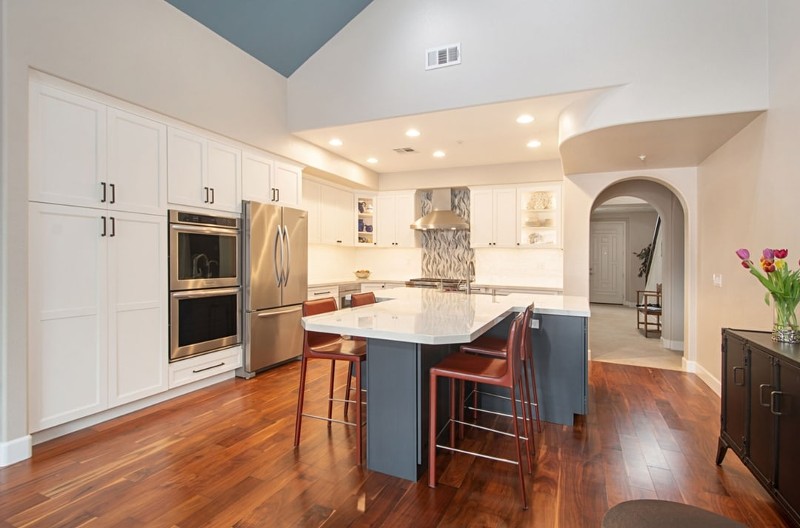 remodeled kitchen with white cabinets, cherry floors, dark blue island, stainless appliances