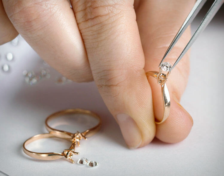 A jeweler sets a diamond in a gold band