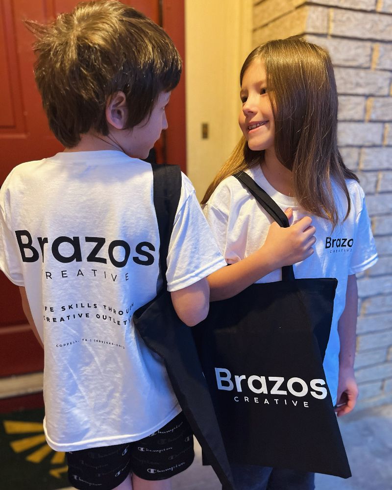 Two students in Brazos Creative t-shirts smiling at each other.
