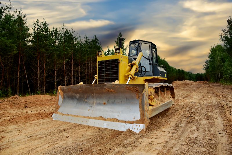 An excavator sits on a cleared lot.