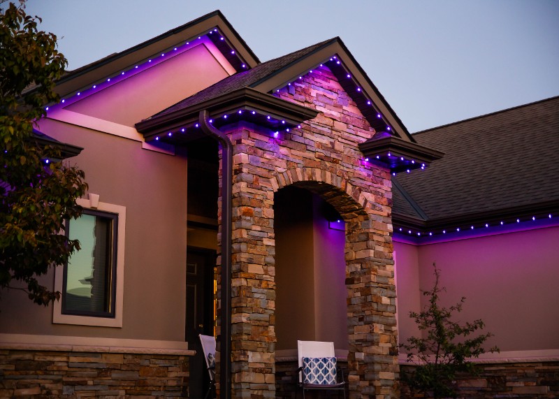 Trimlight lighting set to purple on a brown home.